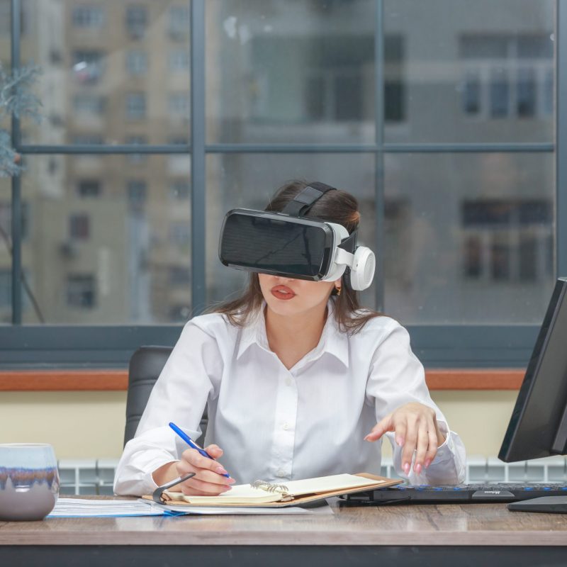 Amazed young woman wearing VR and writing. High quality photo